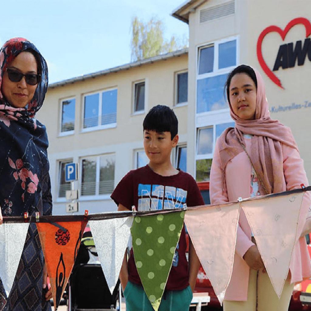 Drei Migrant*innen vor einem interkulturellen Zentrum der AWO
