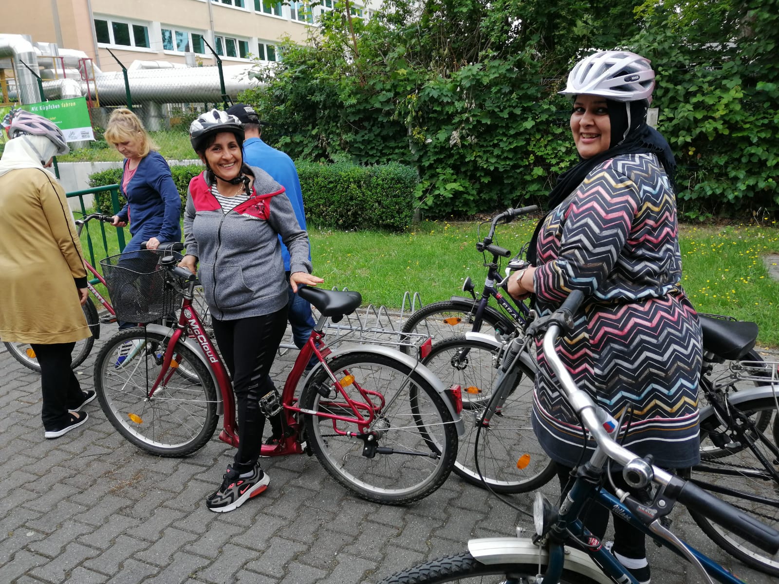 Zwei Frauen halten ihre Fahrräder und lächeln.
