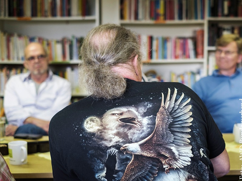 Ein Mann sitzt an einem Tisch zwei Männern gegenüber in einem Gespräch Beratung