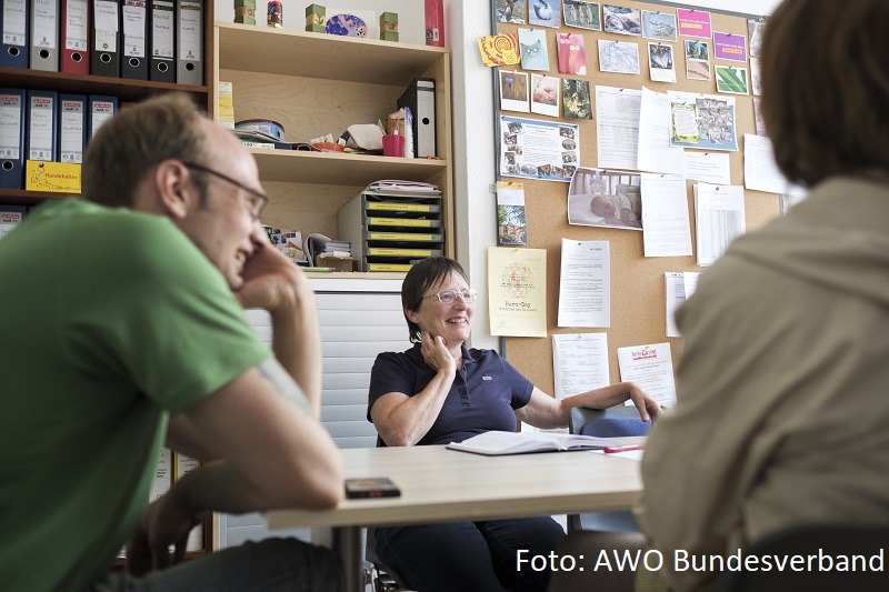 Eine Frau sitzt am Tisch und beratet 2 Personen