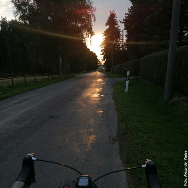 kleine Straße mit Fahrradlenker bei Sonnenuntergang
