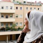 Eine Frau auf einem Balkon blickt nachdenklich auf den Horizont