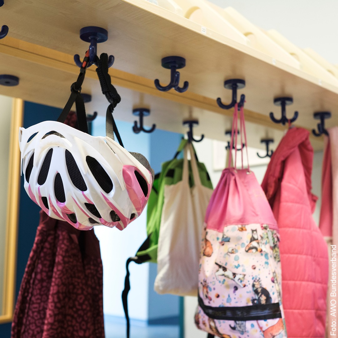Ein Fahrradhelm, Taschen und Jacken hängen an einer Garderobe
