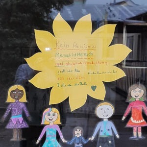 Figuren gegen Rassismus am Fensterbrett in der Mitte eine gelbe Blume