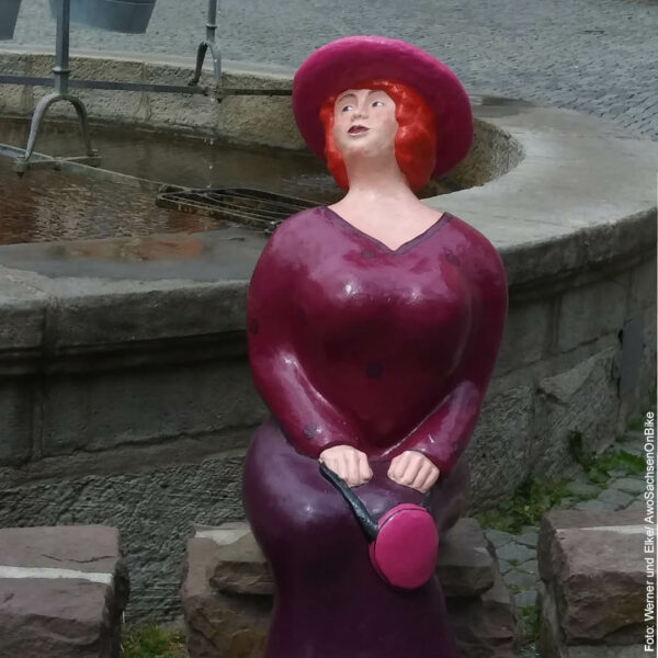 eine Porzellan-Deko Dame sitzt am Brunnen