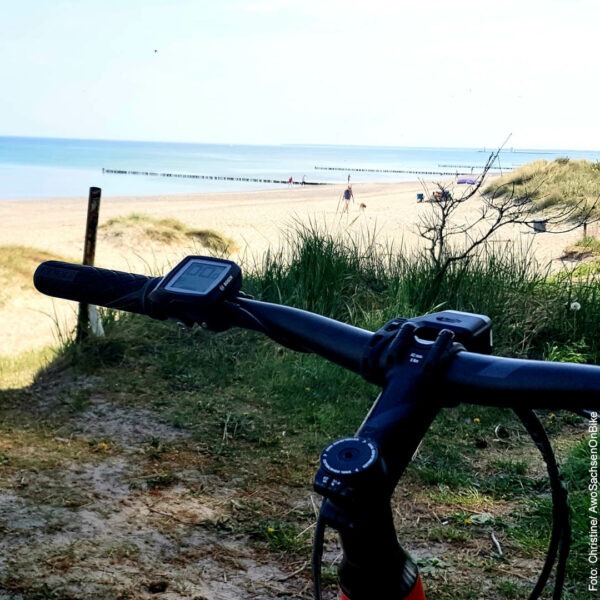Fahrradlenker im Vordergrund, hinten Sandstrand