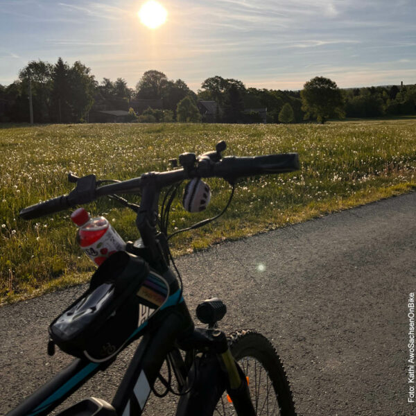 Fahrradsattel und Vorderrad auf dem Fahrradweg, die Sonne geht langsam unter