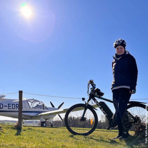 Kathi mit dem Fahrrad vor einem kleinen Flugplatz