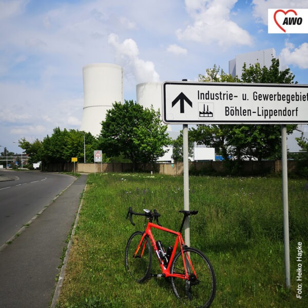 rotes Fahrrad lehnt an Straßenschild, auf dem steht: Industrie und Gewerbegebiet Böhlen-Lippendorf