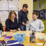 eine Gruppe von fünf Menschen lachend am Tisch