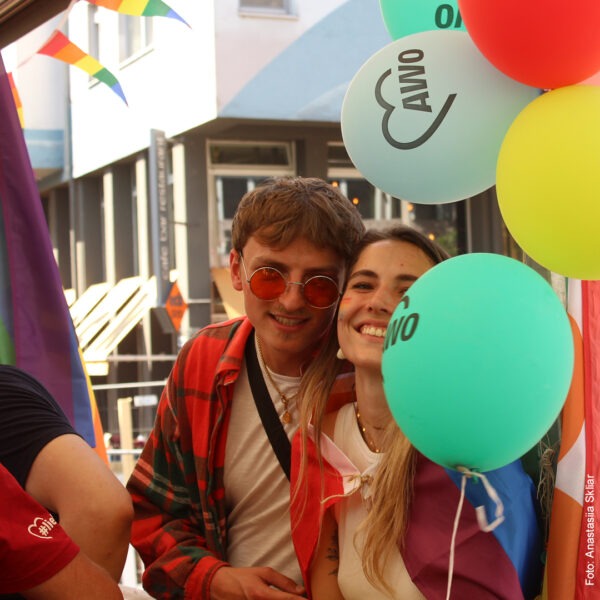 ein junger Mann und eine junge Frau mit AWO Luftballons strahlen in die Kamera