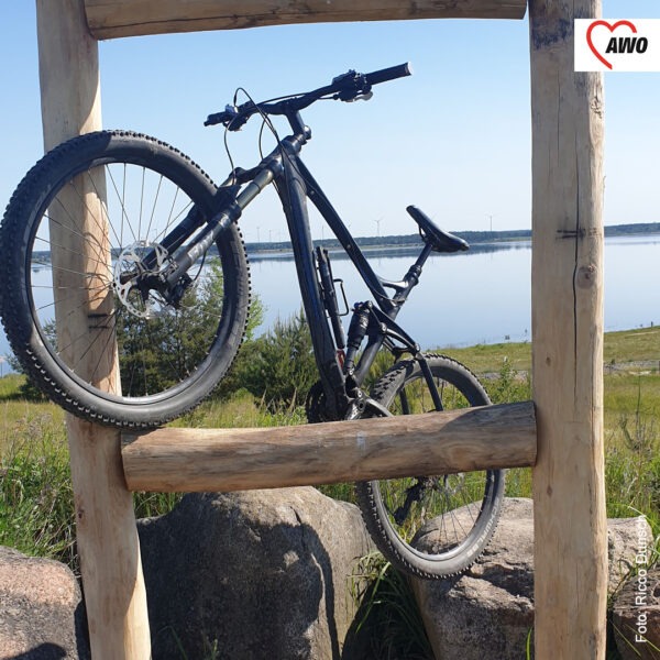Ein Fahrrad lehnt auf einer Holzkonstruktion vor einem See