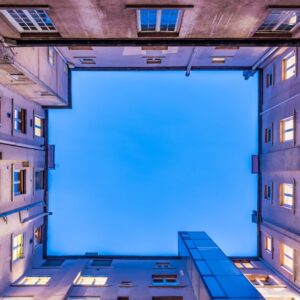 Blick aus einem Innenhof nach oben in den Himmel, es dämmert, Häuser an der Seite