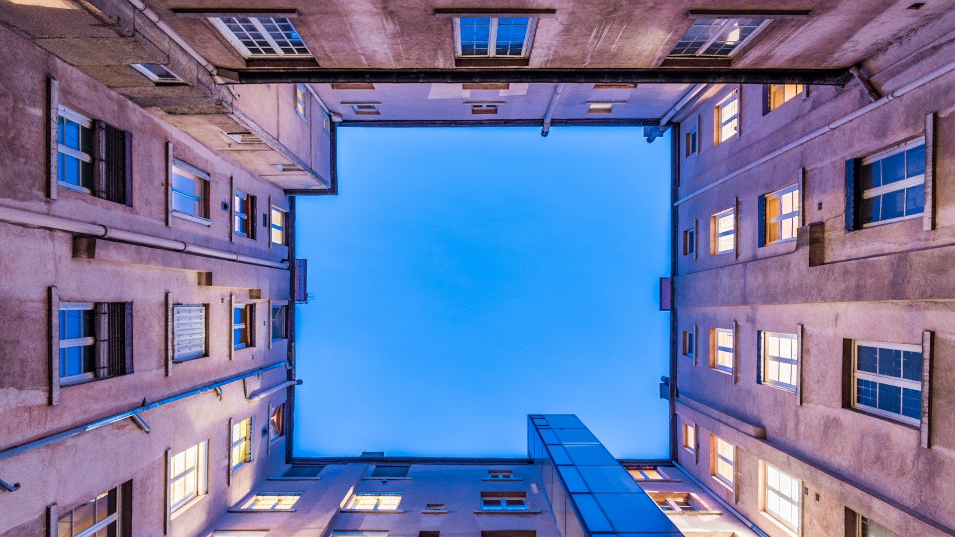 Blick aus einem Innenhof nach oben in den Himmel, es dämmert, Häuser an der Seite