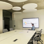 Ein Mann im Rollstuhl tippt das interaktive Whiteboard an