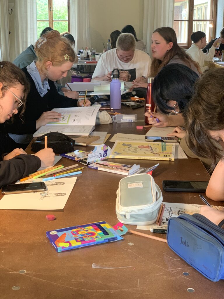 Jugendliche sitzen an einem Tisch und basteln gemeinsam während eines Seminars im Jugendfreiwilligendienst