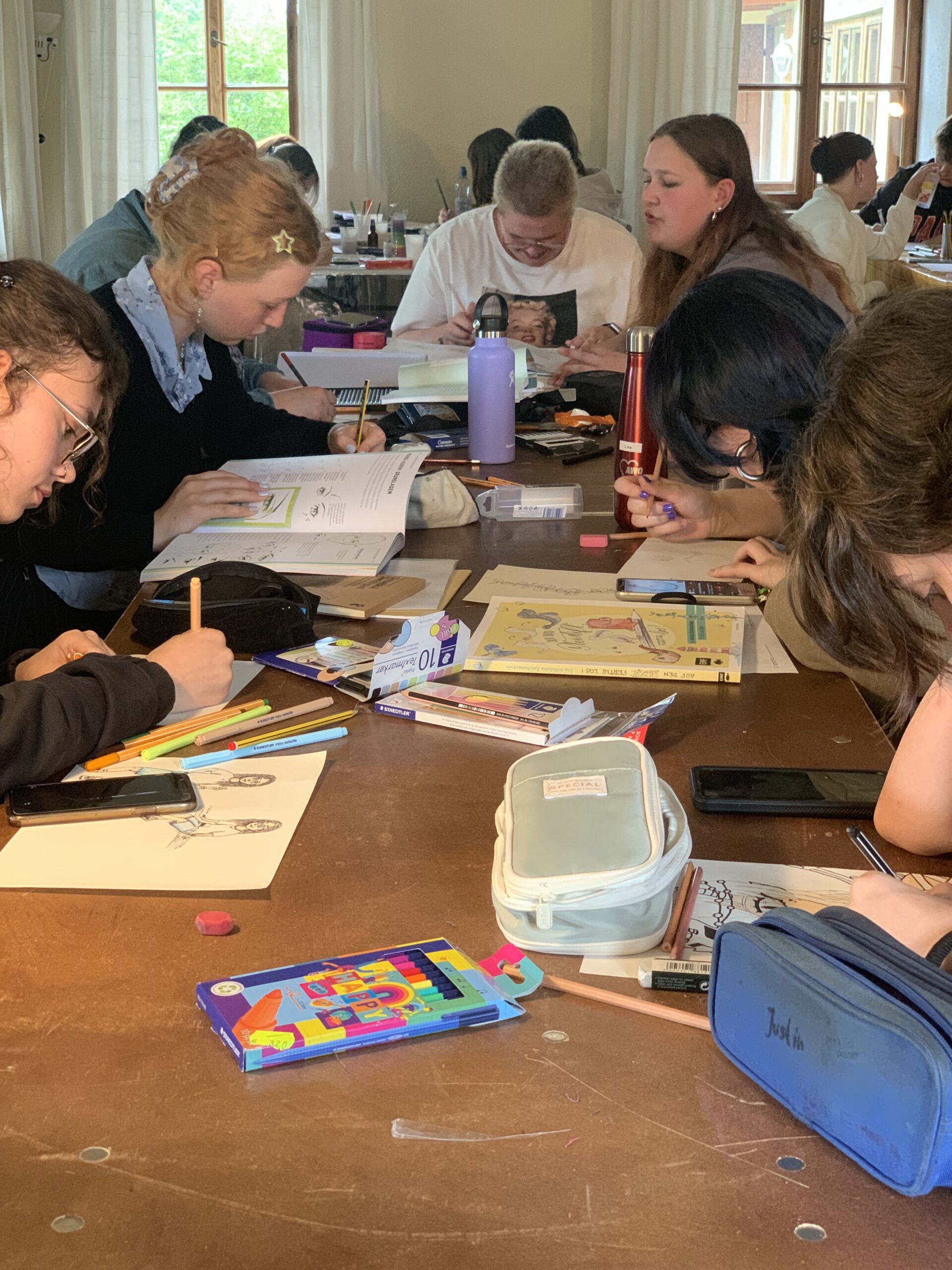 Jugendliche sitzen an einem Tisch und basteln gemeinsam während eines Seminars im Jugendfreiwilligendienst