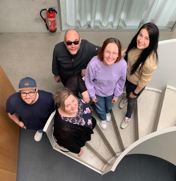 Das Projektteam steht gemeinsam auf einer Treppe und blickt nach oben.