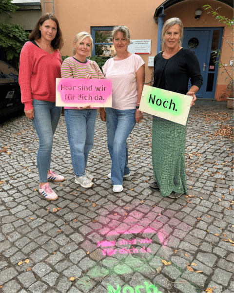 Vier Beraterinnen der AWO-Schwangerschaftsberatung Striesen stehen vor der Einrichtung. Zwei halten Schilder mit der Botschaft ‚Hier sind wir für dich da. Noch